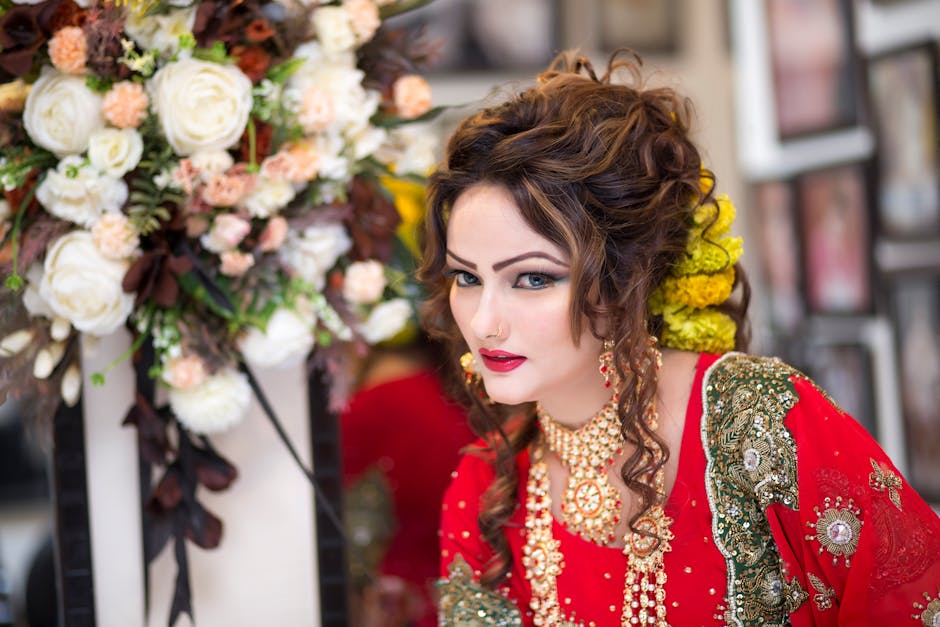 Beautiful South Asian bride in red traditional attire with floral bouquet, showcasing exquisite cultural style.