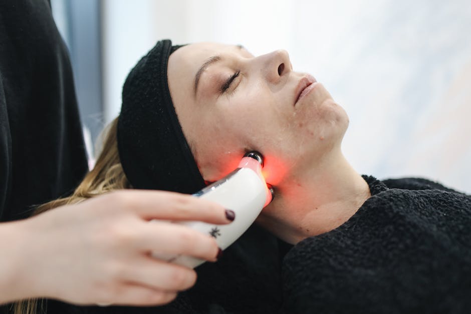 An adult woman receives a laser facial treatment in a modern skincare clinic.