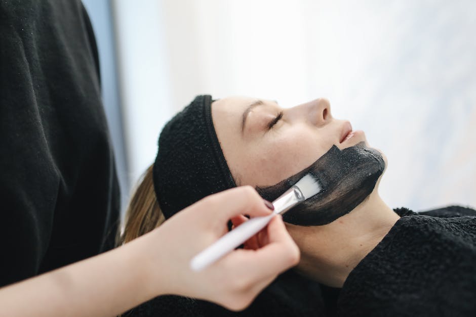 Close-up of a woman enjoying a relaxing charcoal facial treatment in a spa