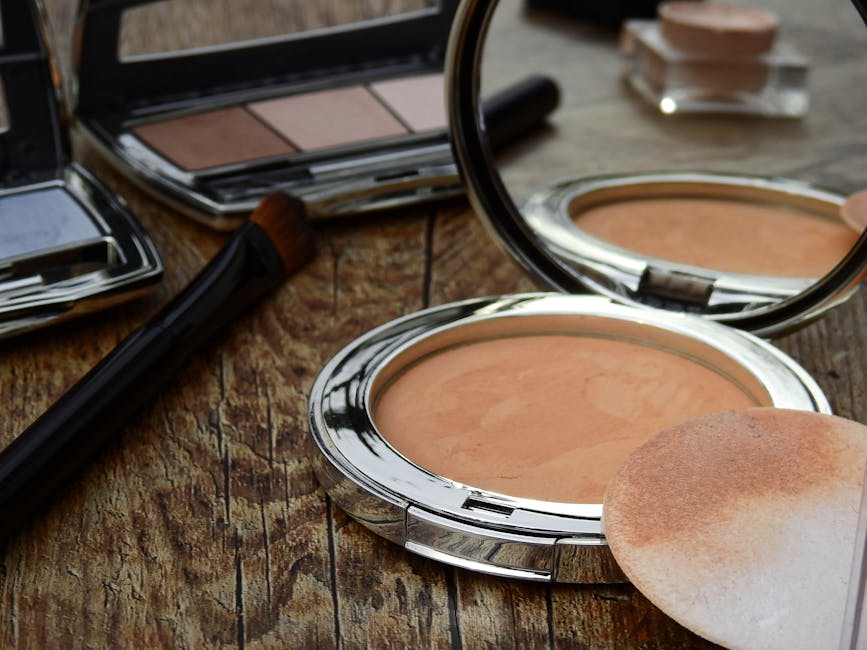 Close-up of makeup tools including compact, brush, and mirror on a rustic wooden surface