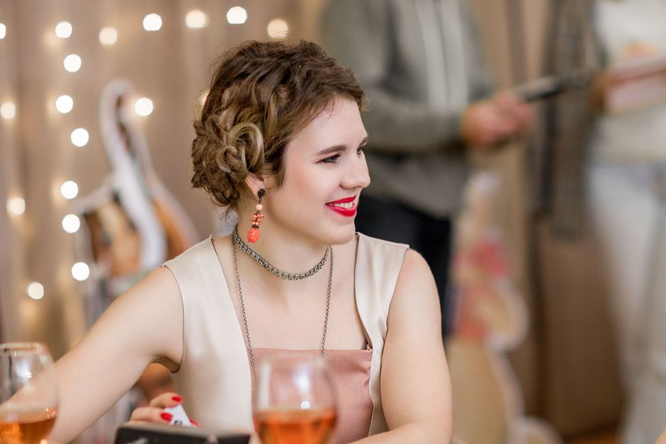 Nasmijana odrasla žena uživa na žurki uz pjenušac i tople svjetla u zatvorenom prostoru