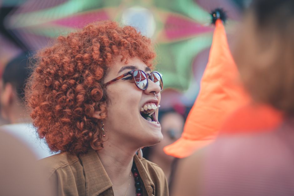 Nasmijana žena s kovrčavom kosom uživa na vanjskom festivalu